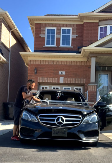 Rami from Ran Auto Glass is working on a black Mercedes sedan e350 in a customer house driveway